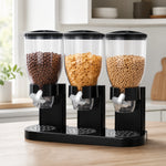Dispensador de cereal triple en negro, con tres depósitos llenos de distintos cereales, sobre una mesa de cocina