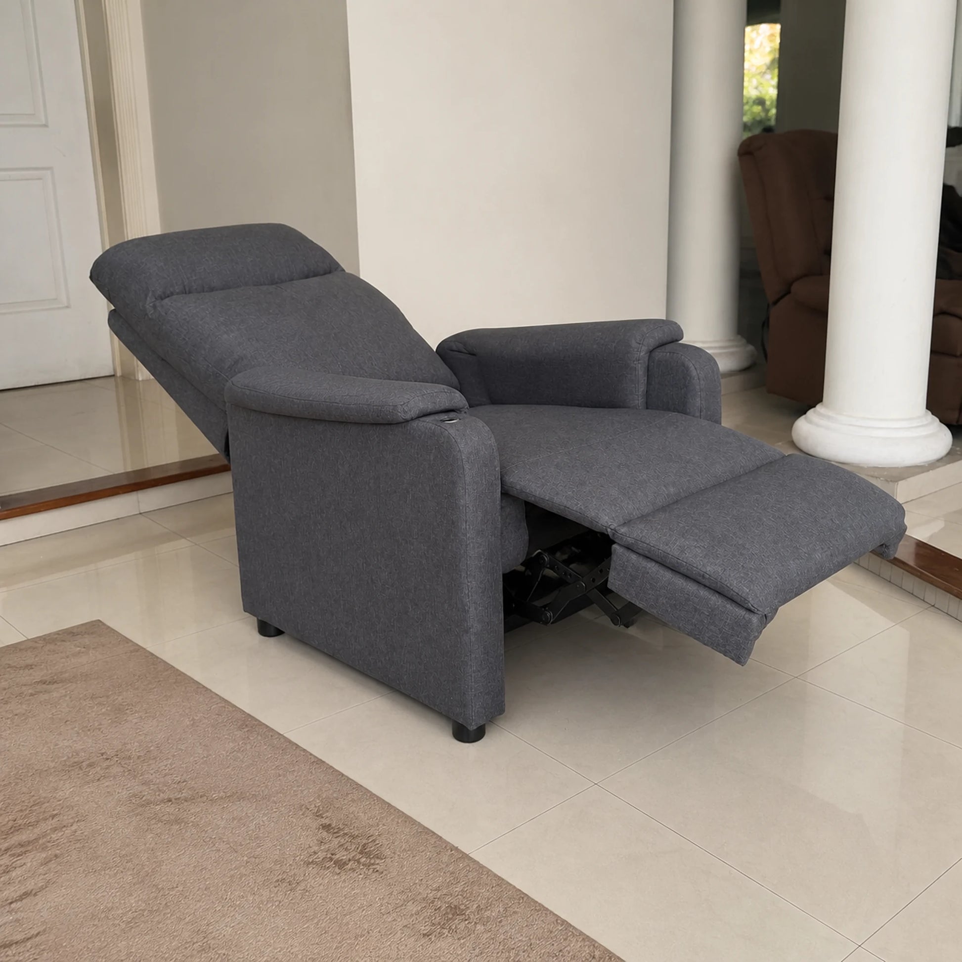 Sillón reclinable en gris completamente reclinado con el reposapiés extendido