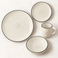 Vista superior de un puesto de la vajilla Lotus color Crema: plato llano, plato de postre, tazón y taza