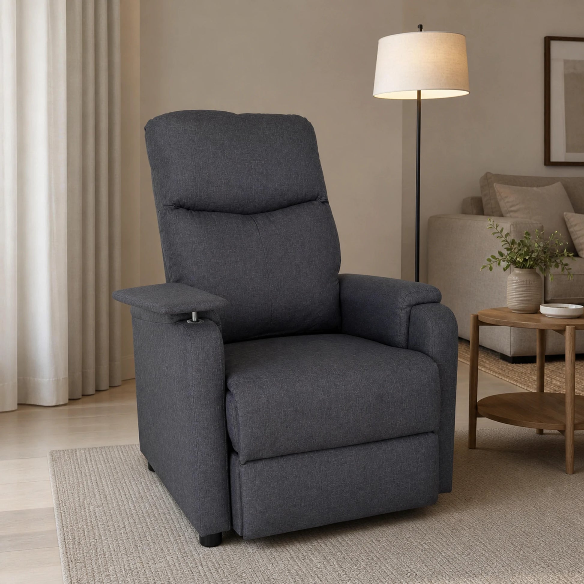 Sillón reclinable en gris ambientado en una sala, mostrando su tamaño junto a otros muebles