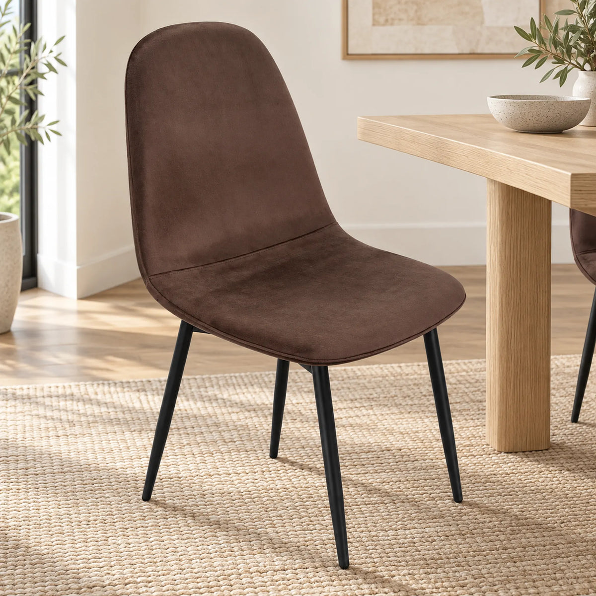 Silla Beneli tapizada en chocolate junto a una mesa de comedor de madera
