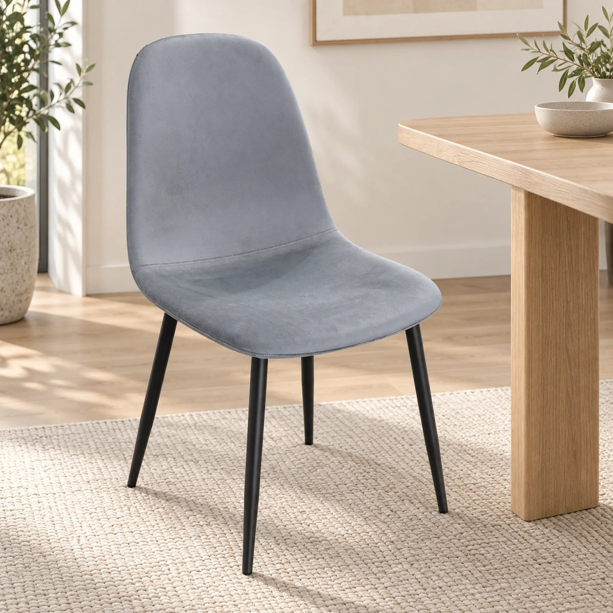 Silla Beneli tapizada en gris claro junto a una mesa de comedor