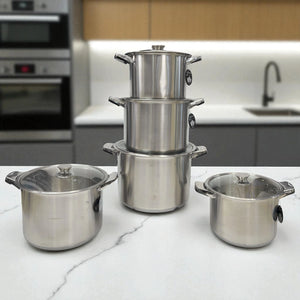 Juego de ollas Epicure de 10 piezas en acero inoxidable con tapas de vidrio, apiladas sobre encimera blanca en cocina moderna.