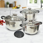 Set de tres ollas MGFR de acero inoxidable con tapas de vidrio y fondo encapsulado, acompañado de un difusor metálico negro, sobre cocina blanca con luz natural