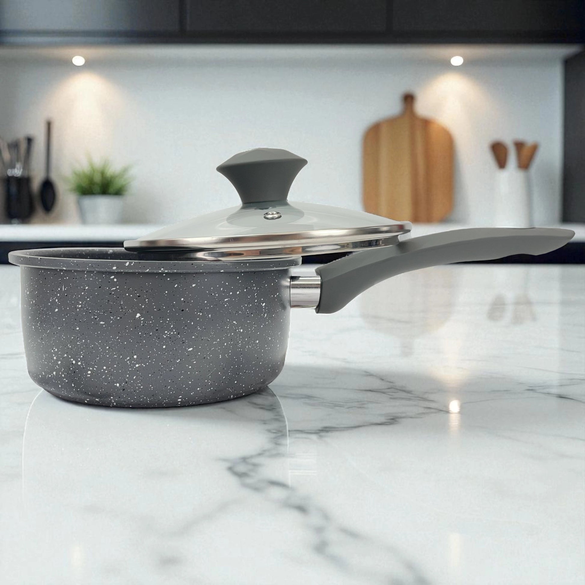 Cacerola con tapa de vidrio del set Big Home gris sobre encimera de mármol en cocina moderna iluminada.