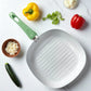 Sartén grill cuadrado con interior blanco y mango verde, ideal para asar carnes y vegetales, marca Lotus Home Collection.