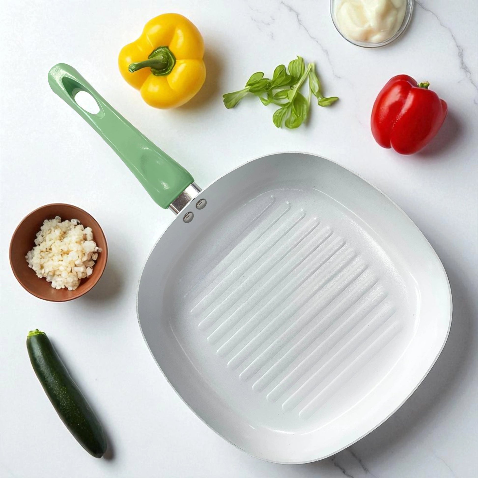 Sartén grill cuadrado con interior blanco y mango verde, ideal para asar carnes y vegetales, marca Lotus Home Collection.