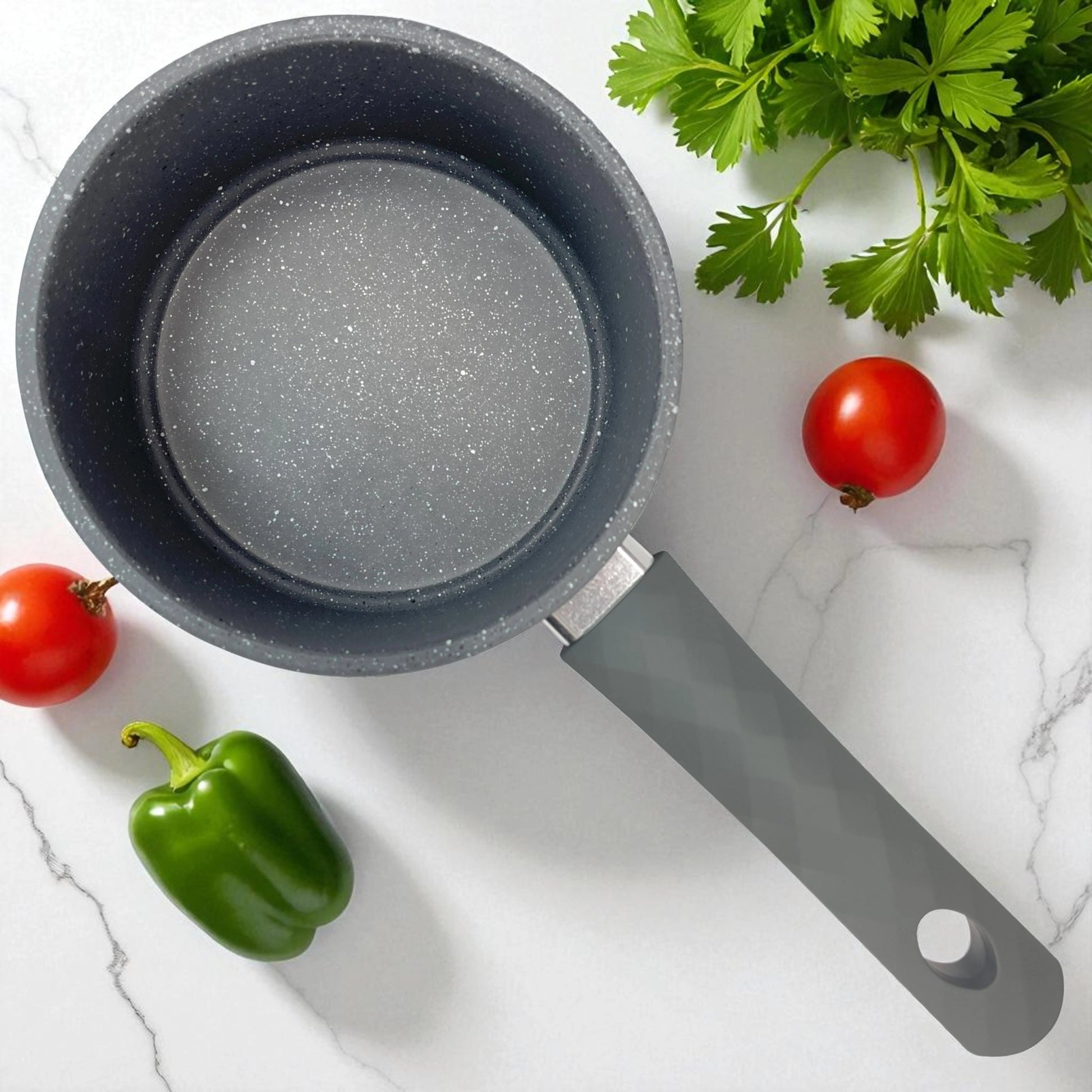 Cacerola Big Home gris en vista superior rodeada de tomate, pimiento verde y hojas de cilantro sobre fondo blanco.