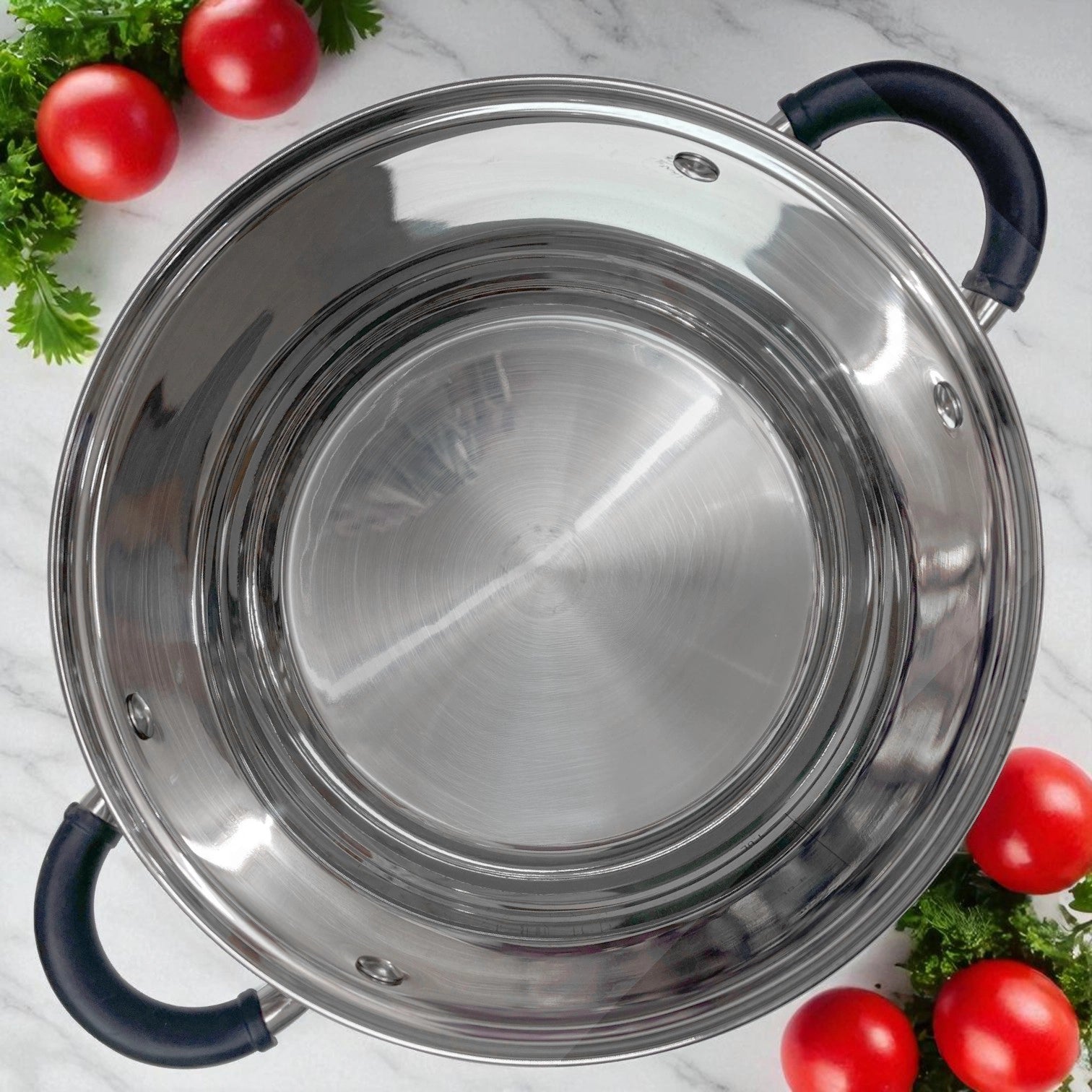 Interior de olla de acero inoxidable MGFR con acabado satinado, asas negras ergonómicas y marcas de capacidad grabadas en el lateral interno, junto a zanahorias y cebolla.