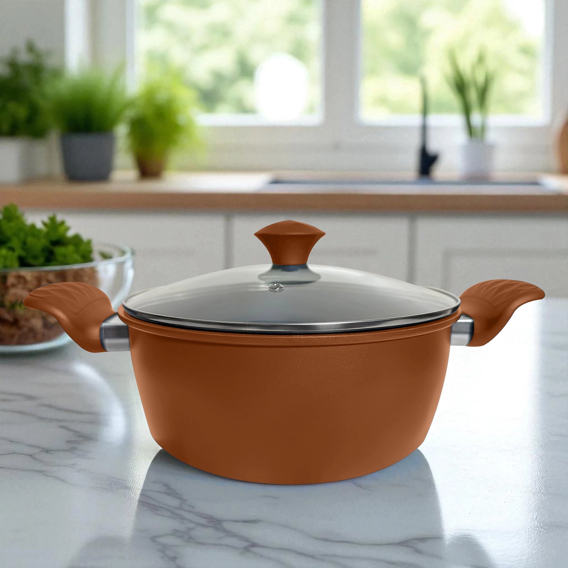 Olla grande color bronce con tapa de vidrio, colocada sobre encimera de mármol en cocina iluminada.