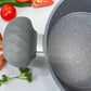 Detalle de la agarradera ergonómica de silicona gris del set de cocina Big Home, con fondo de ingredientes.