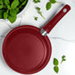 Vista superior del sartén de 14 cm BIG Home con acabado en rojo mate y mango ergonómico, sobre encimera con hojas verdes.