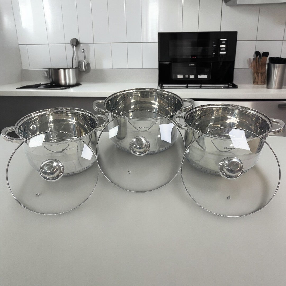 Set de 3 ollas Edel Höff de acero inoxidable con tapaderas de vidrio, exhibidas sobre una encimera de cocina moderna.