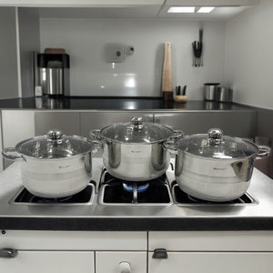 Juego de ollas Edel Höff de acero inoxidable en uso sobre estufa, con tapaderas de vidrio templado.