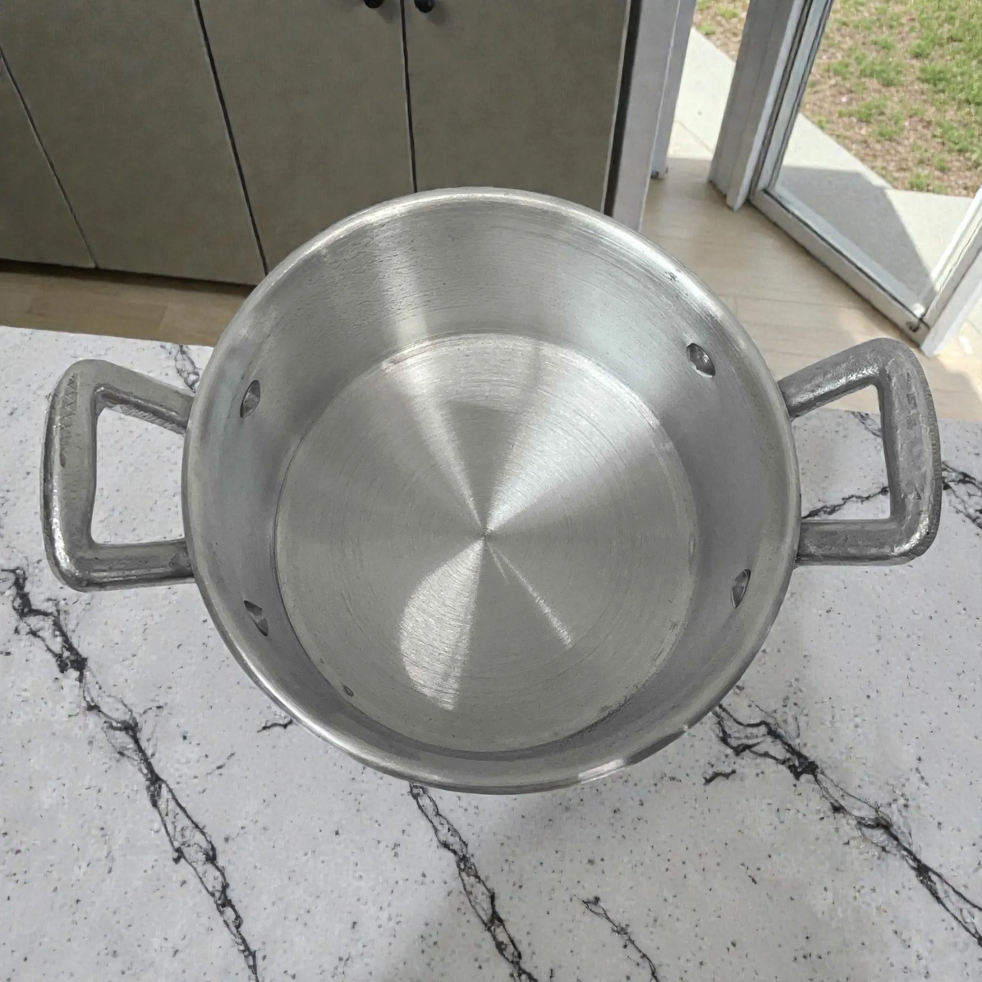 Interior de olla de aluminio ALINTER con oreja #18, color plateado, hecha en El Salvador, vista superior con asas laterales.