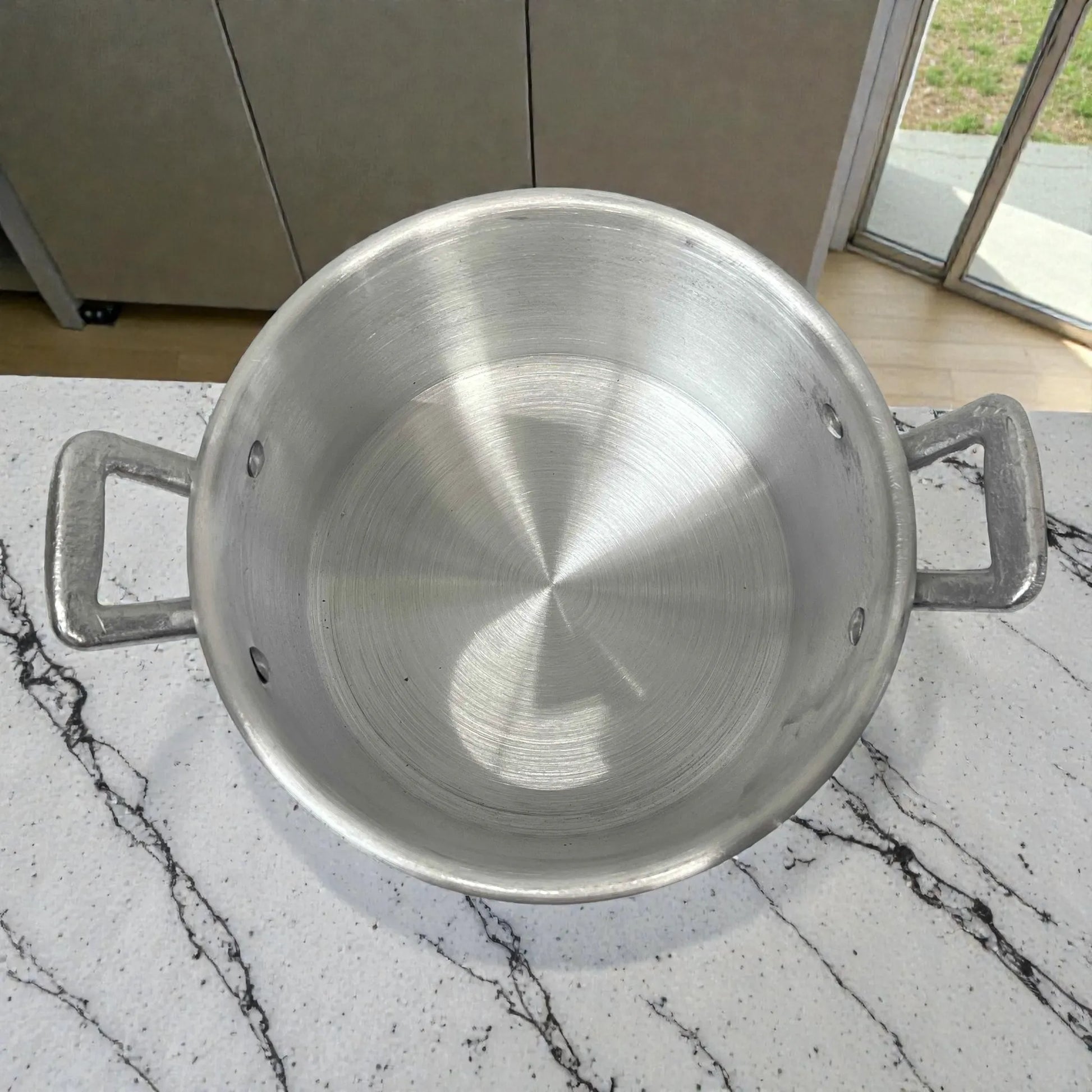 Interior de olla de aluminio ALINTER con oreja #22, color plateado, hecha en El Salvador, vista superior mostrando profundidad y asas.