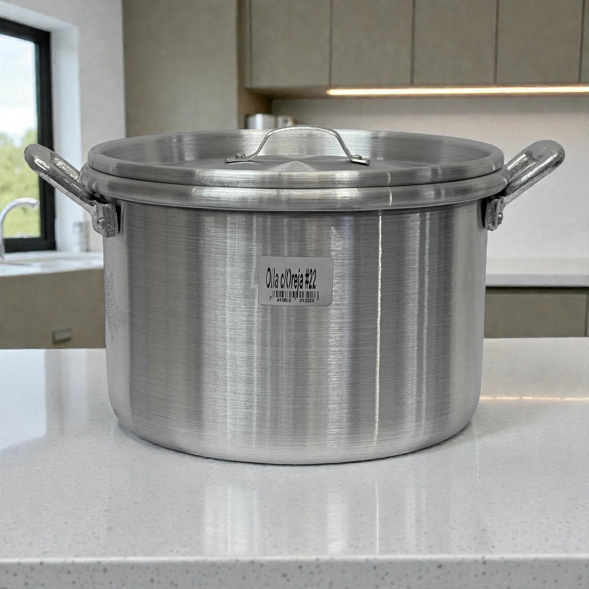 Olla de aluminio ALINTER con oreja #22 y tapa, color plateado, hecha en El Salvador, vista frontal sobre encimera.
