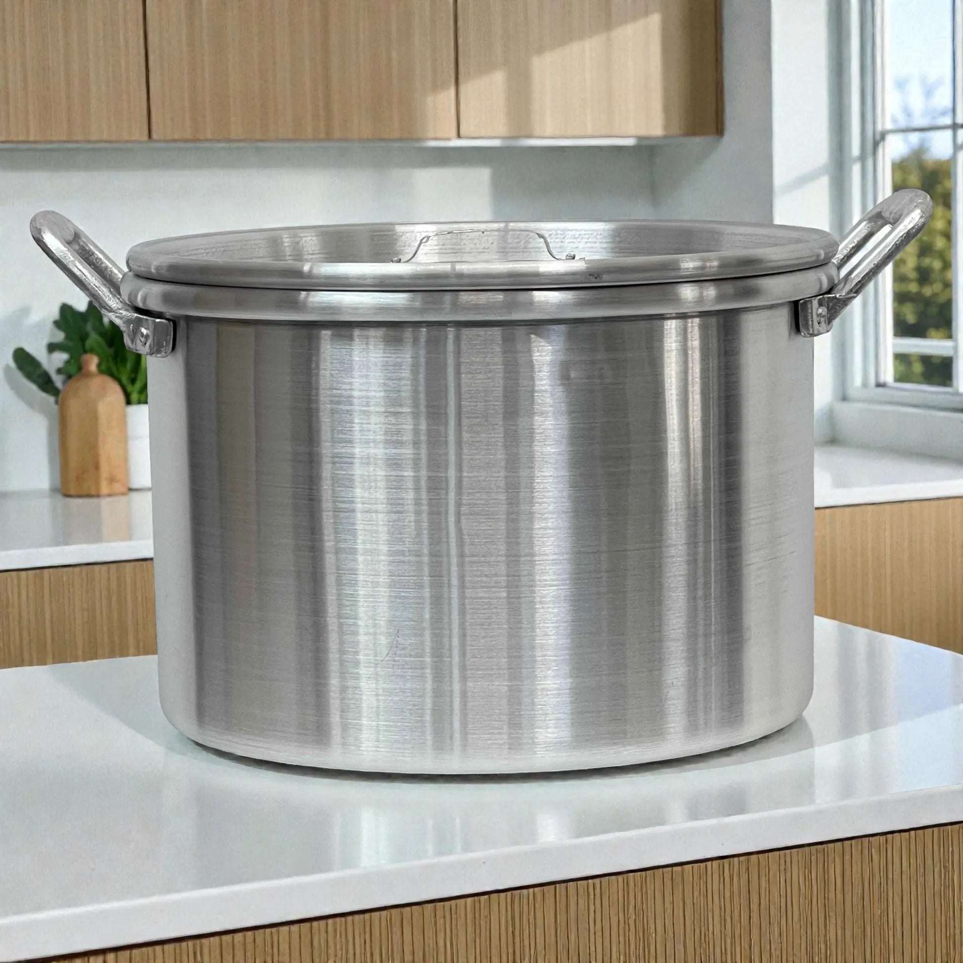 Olla con oreja #38 marca Alinter en aluminio color plateado, con tapa y dos asas laterales, fotografiada de frente sobre encimera en cocina.