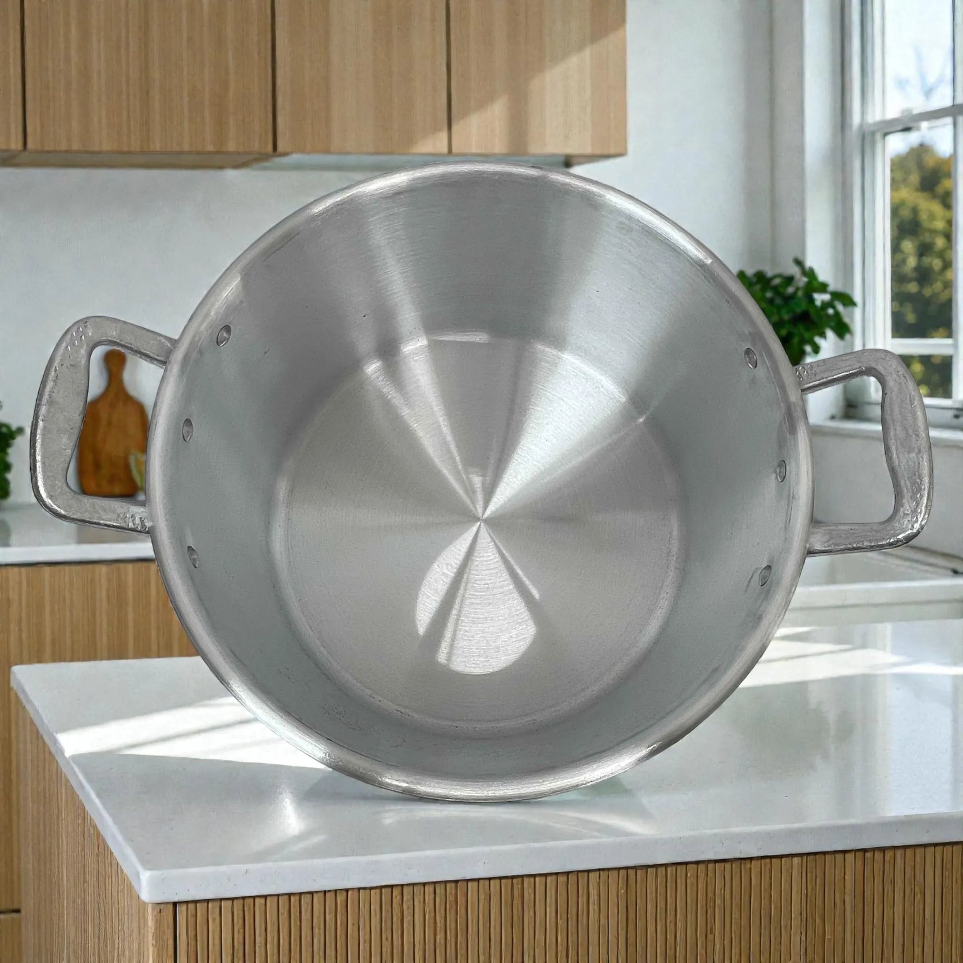 Vista del interior de la olla con oreja #38 Alinter en aluminio plateado, mostrando fondo circular y remaches laterales de las asas, en encimera de cocina.