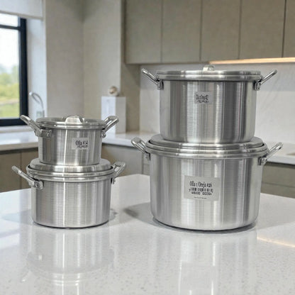 Set de 4 ollas de aluminio ALINTER con oreja y tapa (#14 #18 #22 #26), color plateado, hechas en El Salvador, apiladas sobre encimera en cocina.