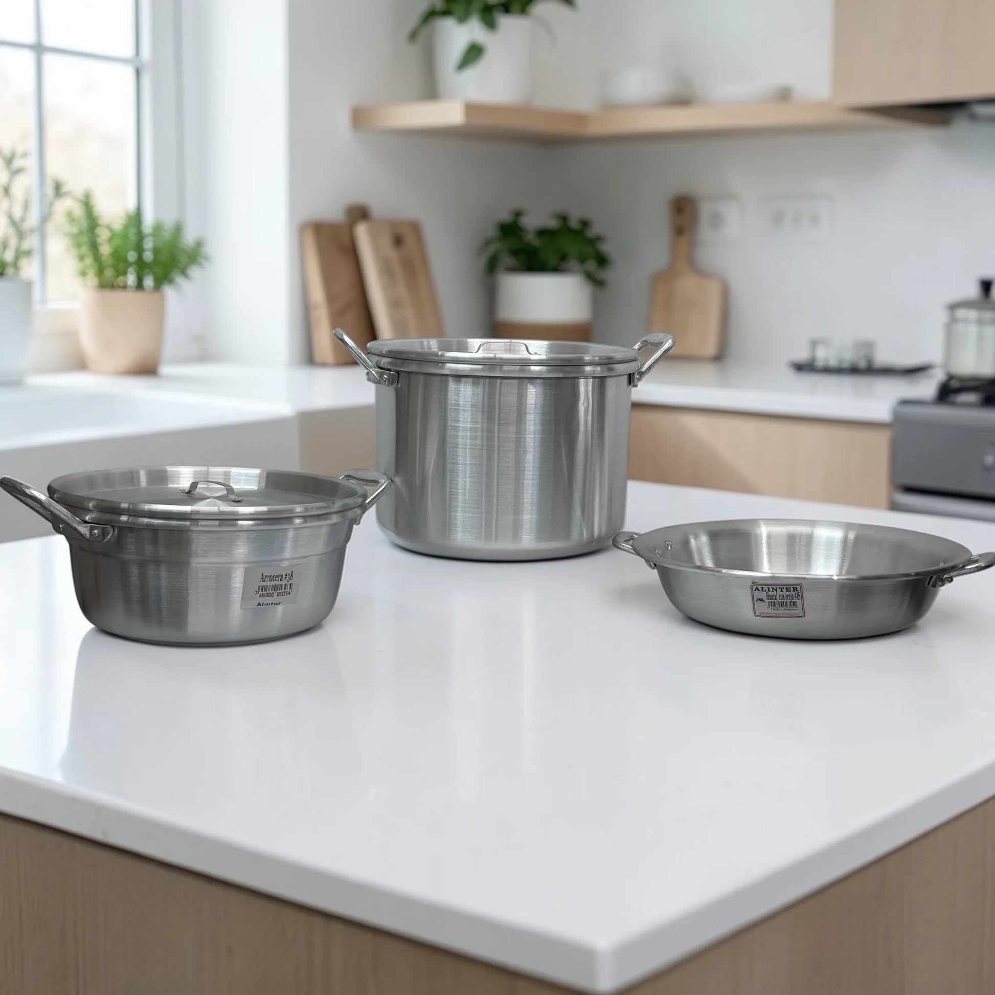 Set Alinter de aluminio SKU OAO3824 en cocina: arrocera #38 a la izquierda con tapa, olla con oreja #38 al centro con tapa y huacal con oreja #45 a la derecha, acabado aluminio plateado.