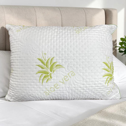 Almohada Aloe Vera Scarlett Classics Standard 51x66 cm color blanco con diseño verde, textura acolchada, hipoalergénica y respirable sobre cama blanca con cabecera beige.
