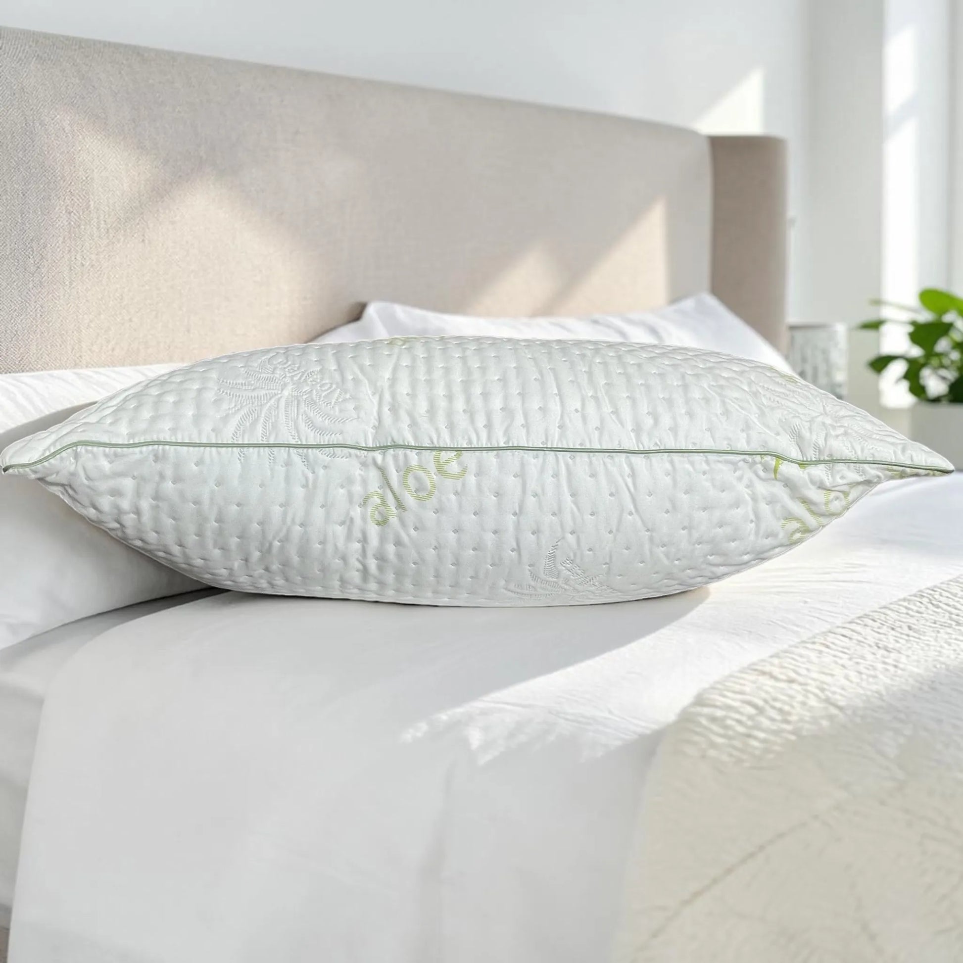 Vista lateral de almohada Aloe Vera Scarlett Classics Standard 51x66 cm mostrando grosor, volumen, borde verde y textura blanca acolchada sobre cama.