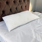 Almohada de bambú Pacific Home blanca de 50 x 90 cm fotografiada en perspectiva diagonal sobre una cama, mostrando su longitud, volumen y textura.