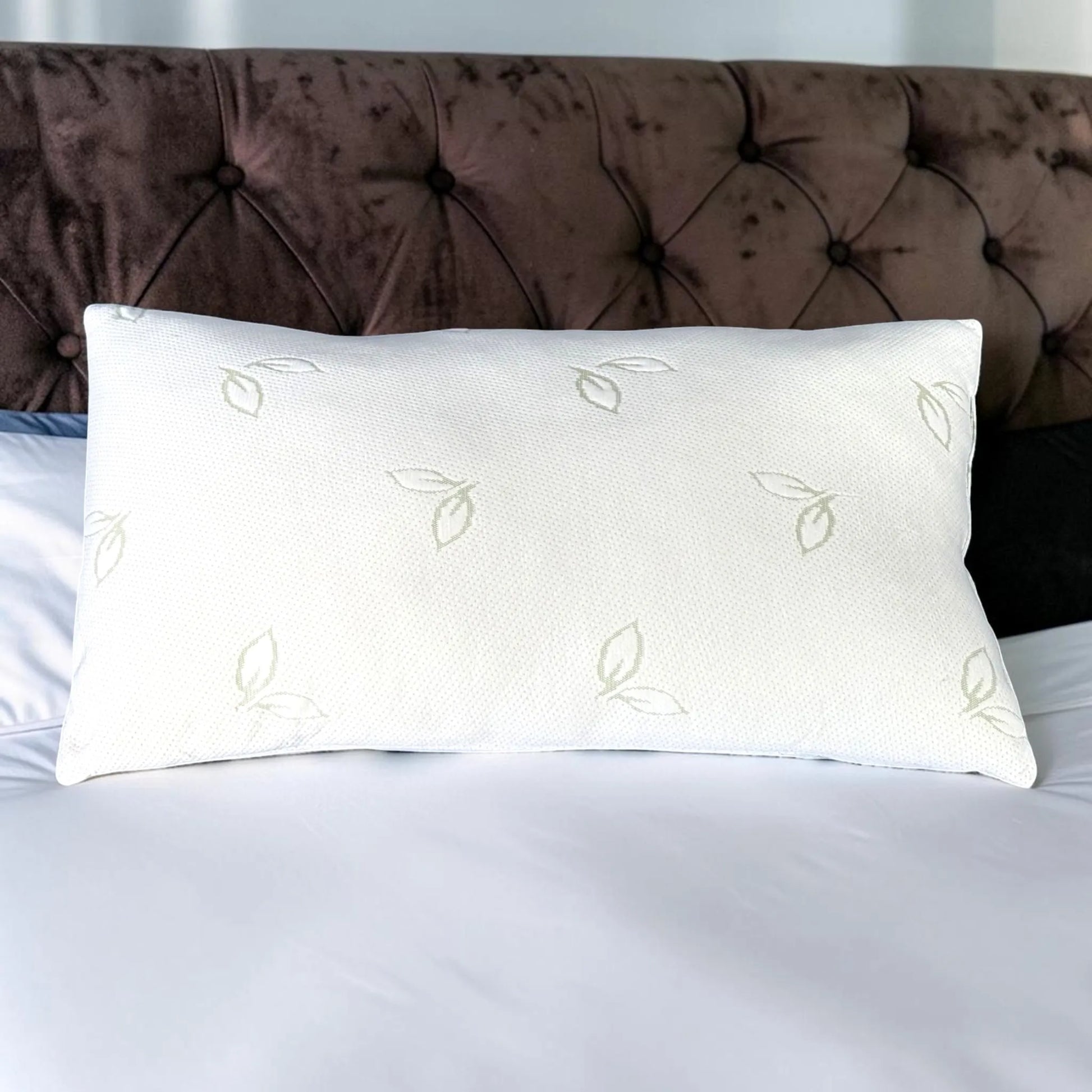 Almohada de bambú Pacific Home blanca de 50 x 90 cm mostrada de frente sobre una cama, con tejido transpirable y diseño de hojas verdes.