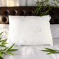 Almohada de bambú Pacific Home color blanco presentada sobre una cama con hojas naturales de bambú alrededor.