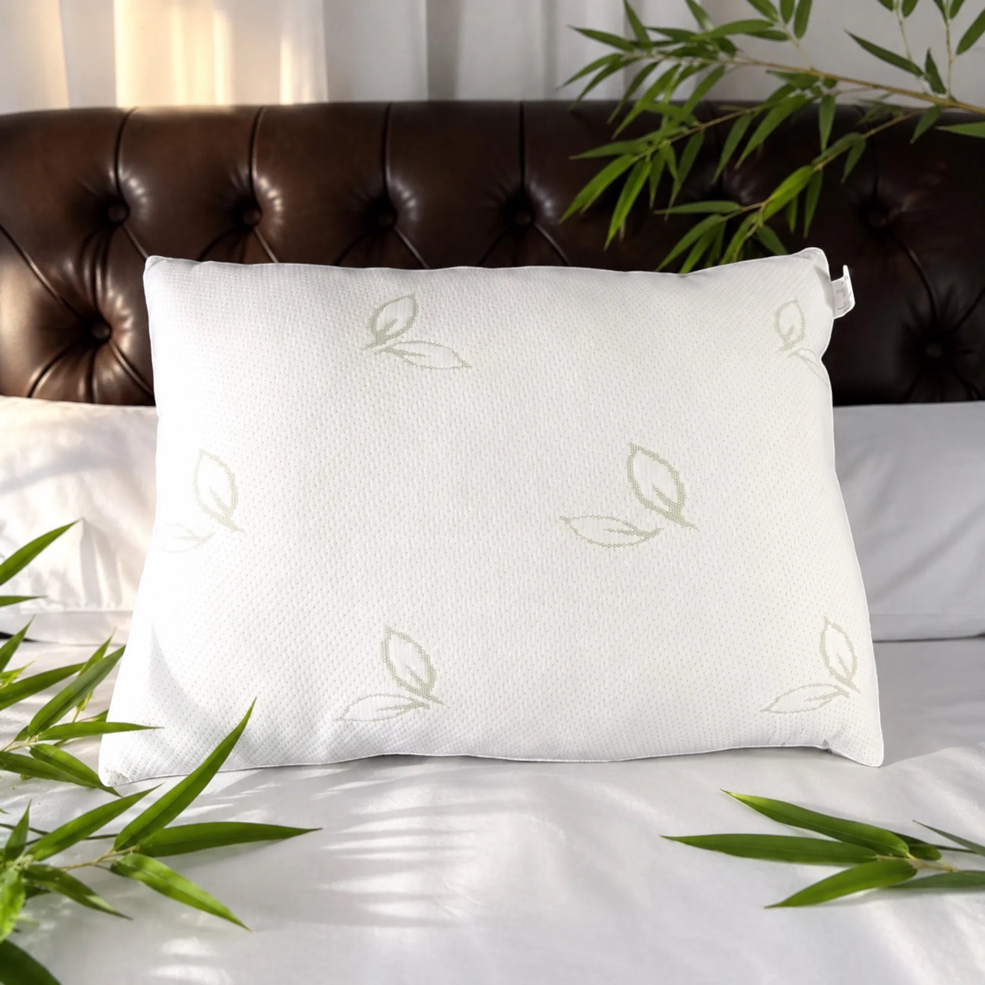 Almohada de bambú Pacific Home color blanco presentada sobre una cama con hojas naturales de bambú alrededor.
