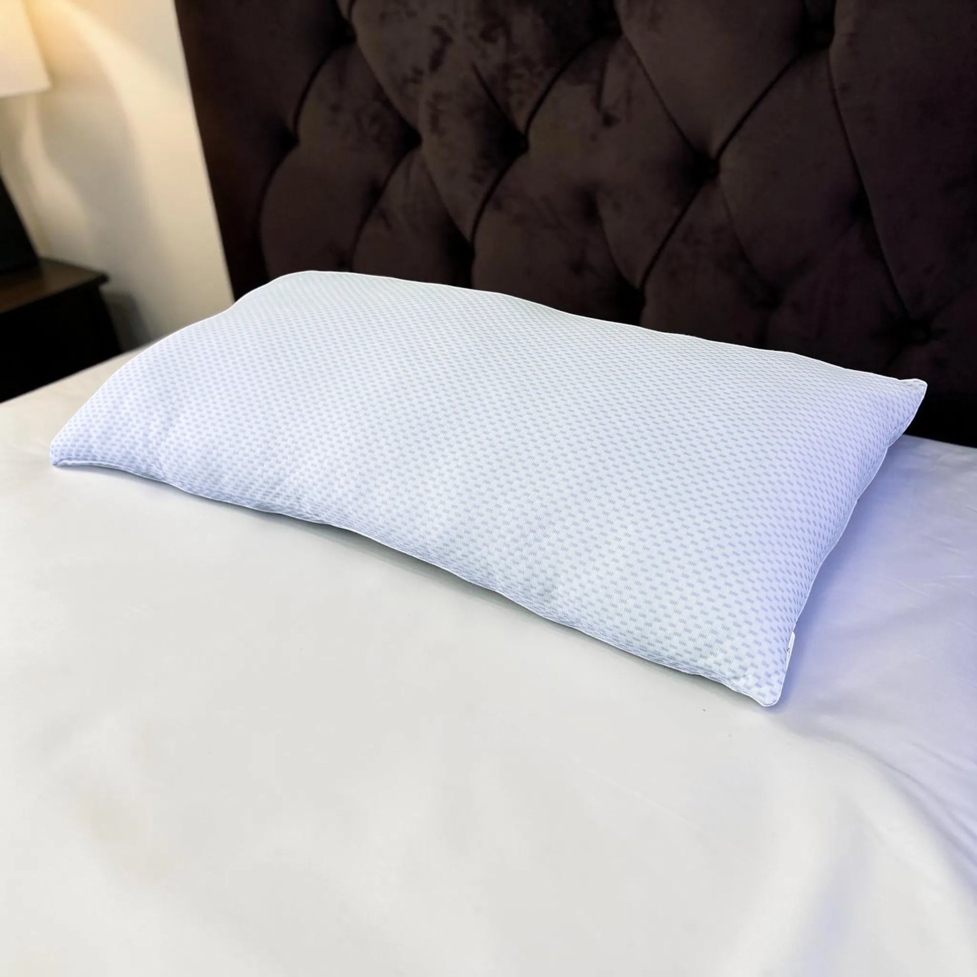 Almohada refrescante Pacific Home blanca con diseño celeste fotografiada en posición diagonal sobre una cama.