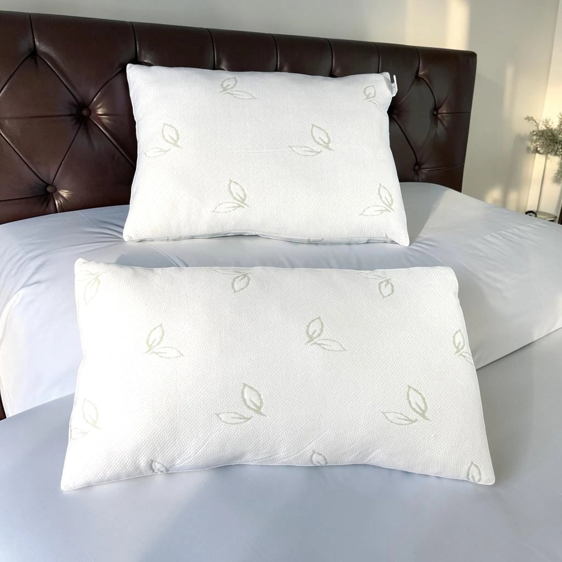 Almohadas de bambú Pacific Home blancas en tamaños 50 x 70 cm y 50 x 90 cm colocadas sobre una cama para comparar sus dimensiones.