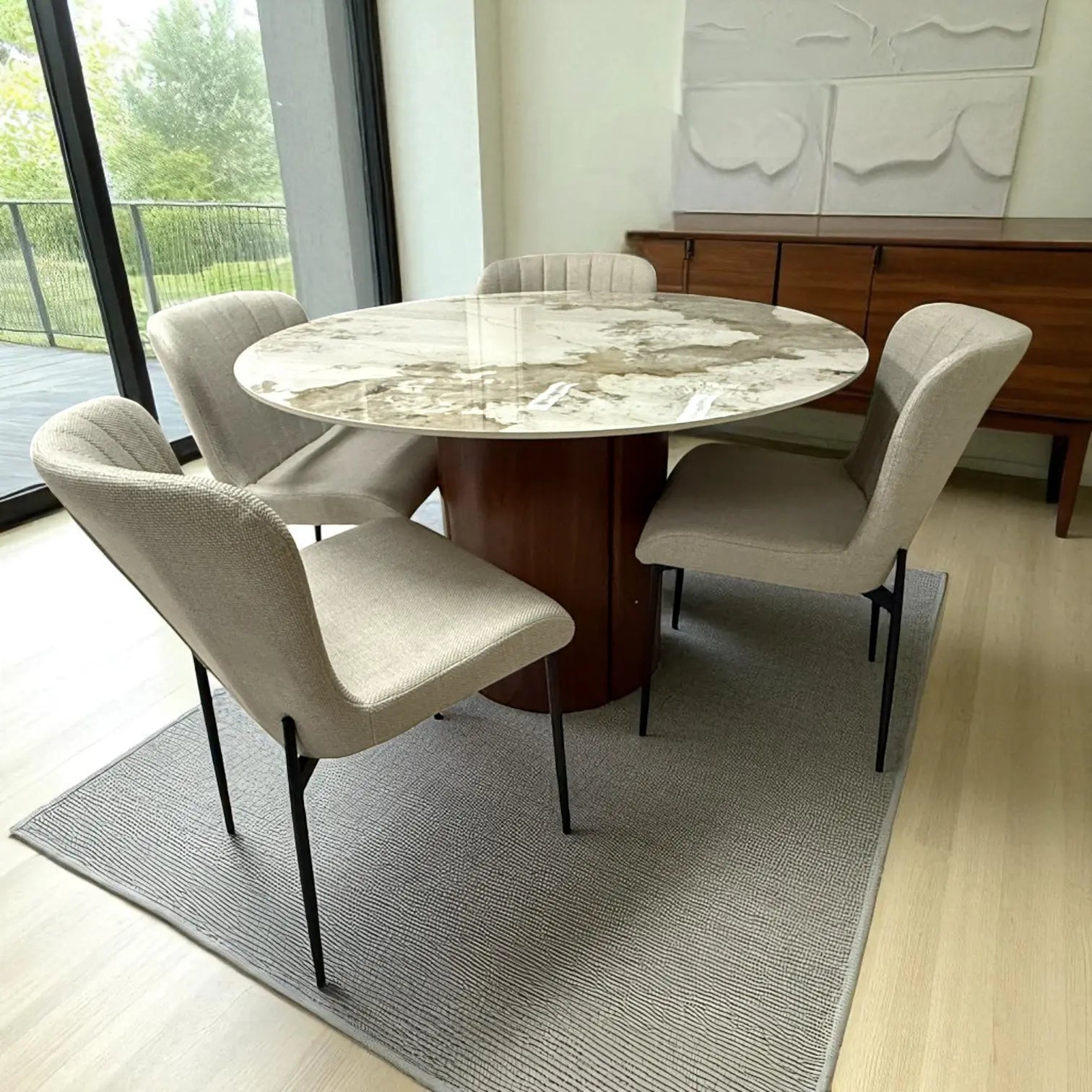 Vista aérea del set DT-04-2258 con mesa Ø120 cm efecto mármol y sillas beige, en ambiente iluminado con cortinas blancas y aparador de madera.