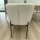 Vista trasera de la silla DT-04-2258 con respaldo curvo tapizado beige y costura central; estructura y patas metálicas negras, altura 82 cm, ancho 55 cm.