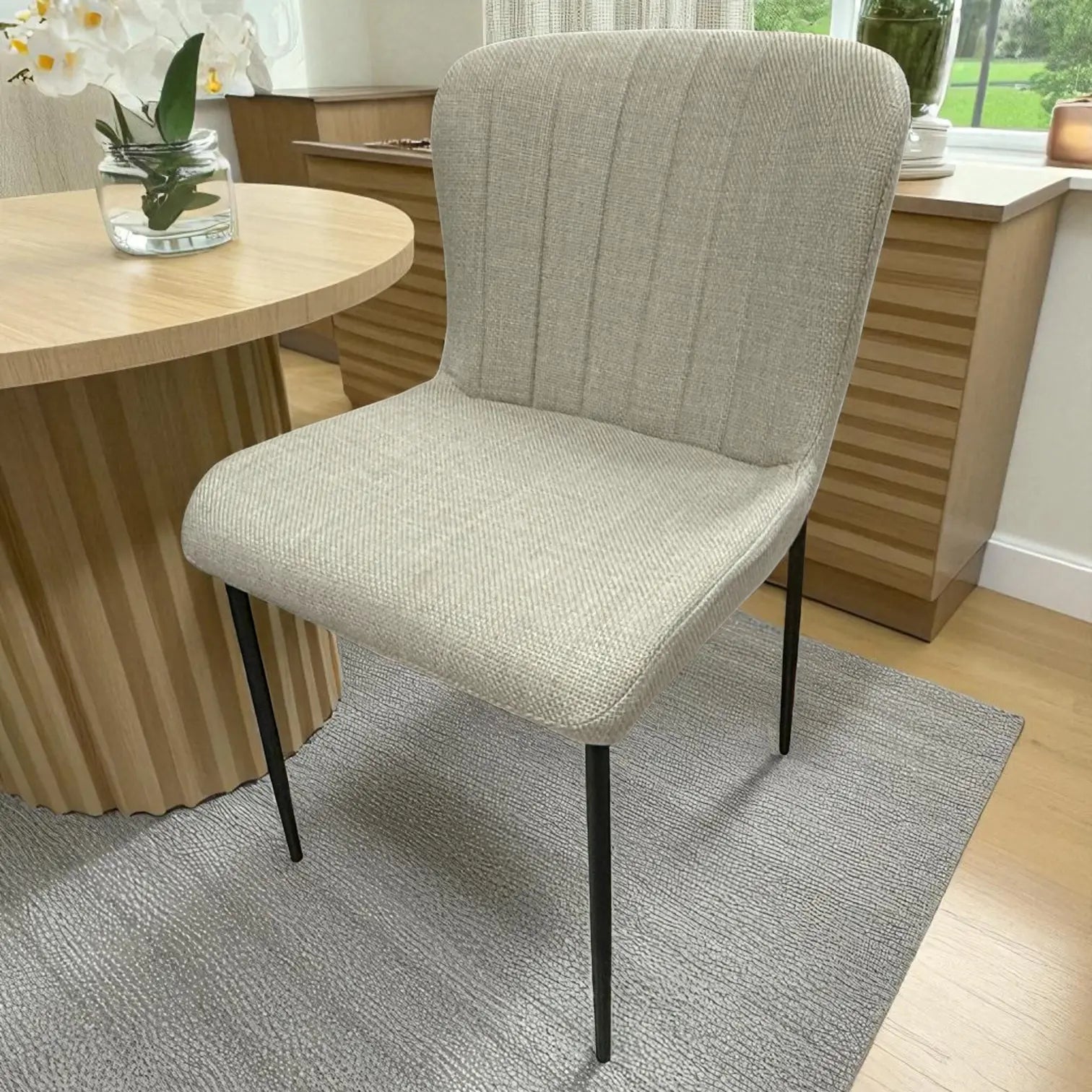 Silla de comedor Ambienta Home Decor DT-04-2258, tapizado beige tipo lino, patas metálicas negras; vista frontal en ambiente junto a mesa redonda, asiento ancho 48 cm, altura total 82 cm.