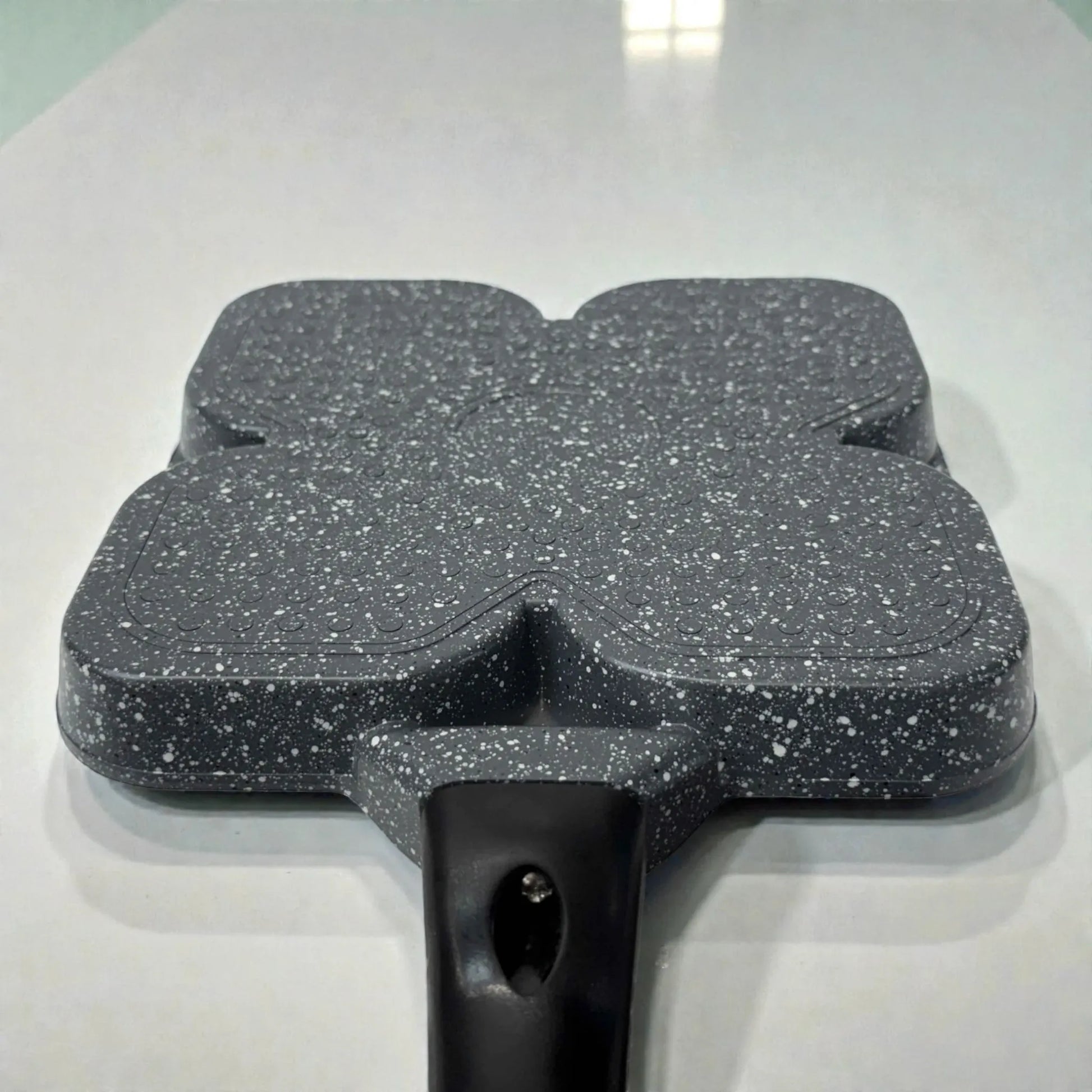 Vista baja de la base inferior del sarten Synamore 5 en 1 en color gris moteado con mango negro, sobre fondo blanco, mostrando la parte exterior del utensilio.