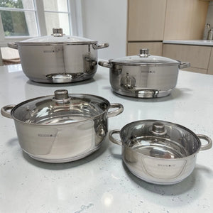 Batería de cocina BergHome Line BL-1465 con 4 ollas de acero inoxidable y tapas de vidrio, color plateado, exhibida en cocina moderna.