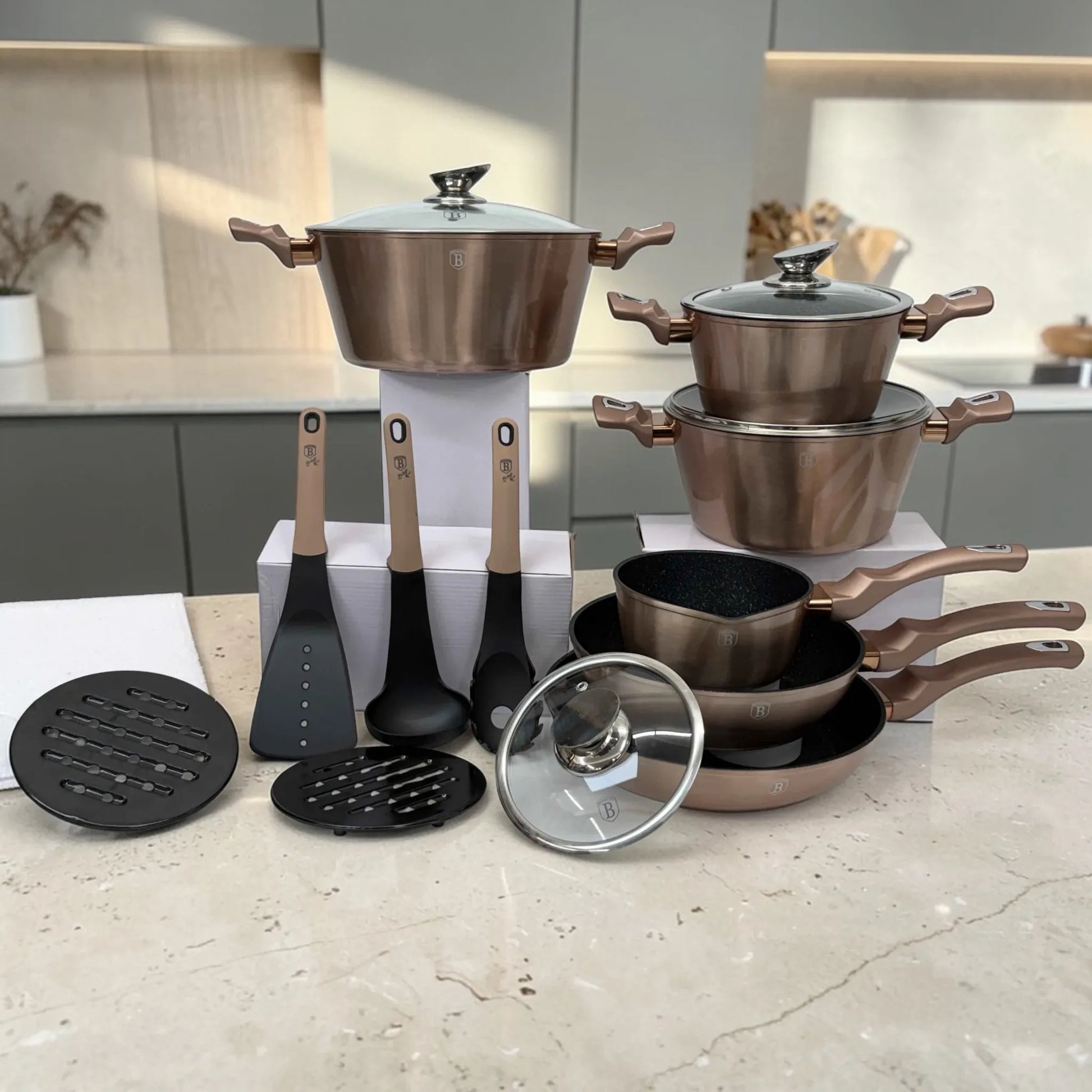 Batería de cocina Berlinger Haus Metallic Line Rosegold BH-1224N con ollas apiladas, utensilios, protectores y tapa de vidrio separada sobre encimera.