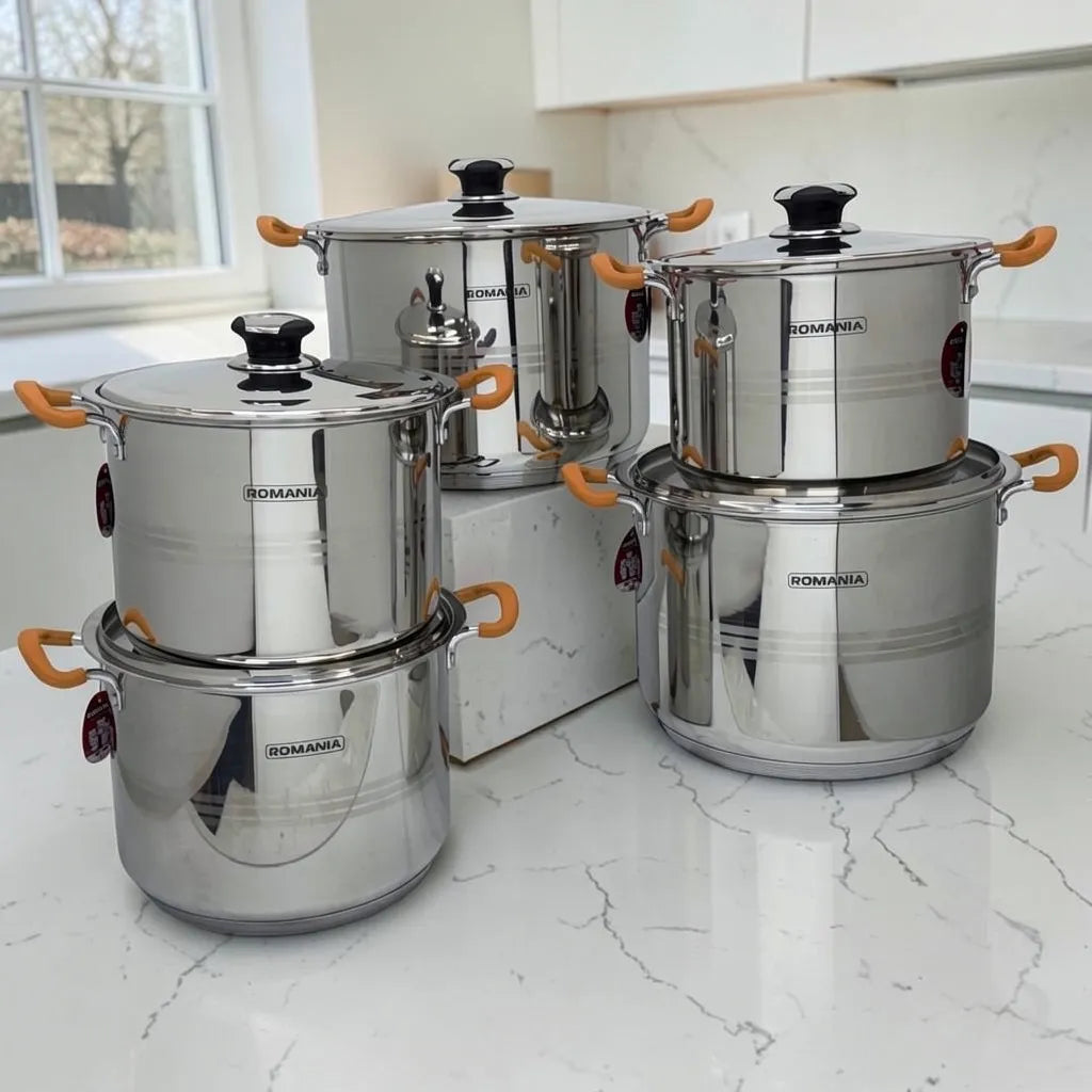 Batería de cocina Romania de 10 piezas en acero inoxidable con mangos naranjas, presentada sobre encimera blanca en cocina moderna.