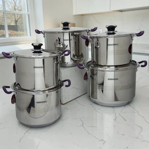 Batería de cocina Romania de 10 piezas en acero inoxidable con mangos púrpura, colocada sobre encimera blanca en cocina moderna.