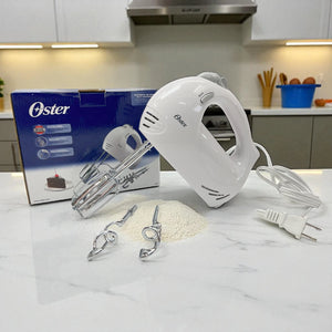 Batidora de mano Oster color blanco de 5 velocidades con batidores y ganchos para masa, vista frontal en cocina.