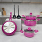Batería Bergmann 9 piezas color fucsia con ollas y cacerolas con tapas de vidrio, sartén con base metálica visible y utensilios incluidos, vista frontal en encimera.
