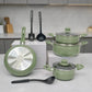 Batería de cocina Bergmann verde oliva con ollas con tapa de vidrio y sartén con base metálica visible, utensilios colocados en cocina.
