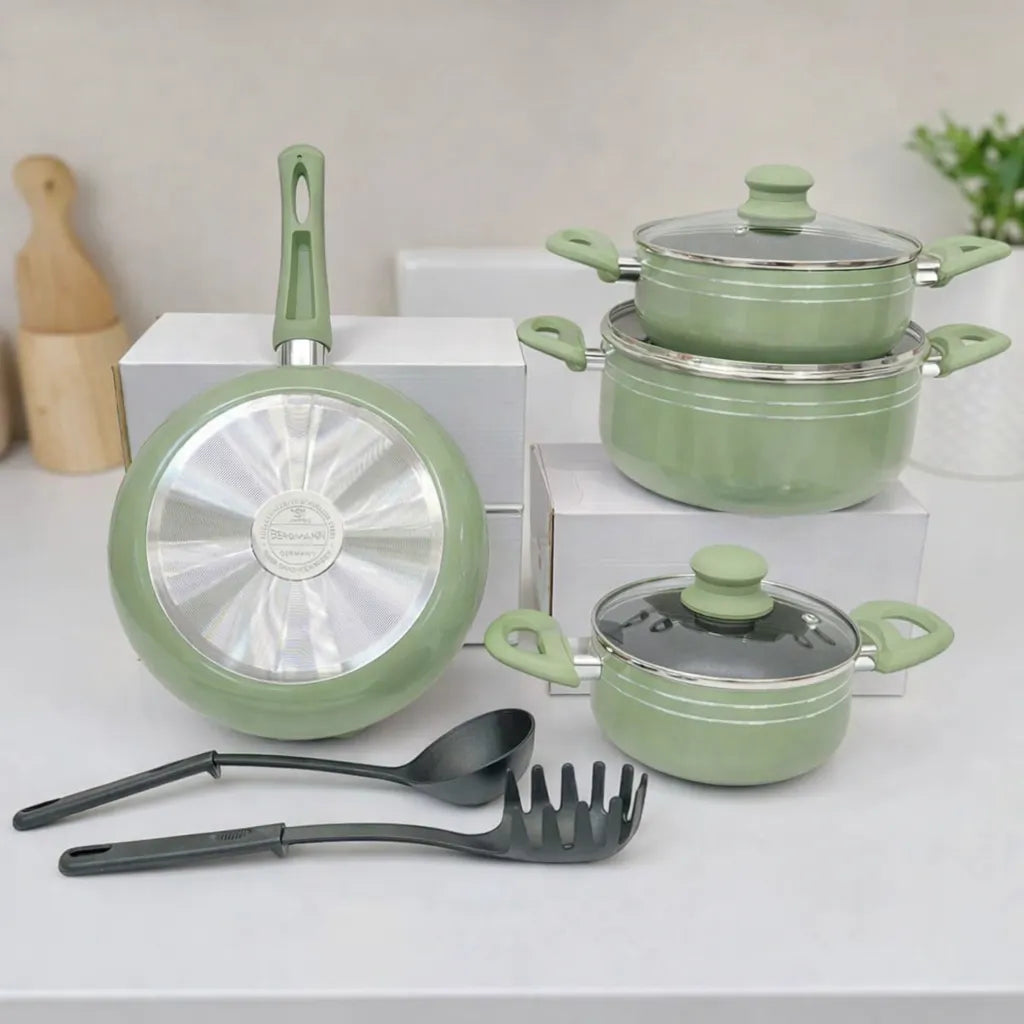 Set de ollas Bergmann verde oliva con tapas de vidrio, sartén con base metálica de acero inoxidable visible y utensilios negros al frente.