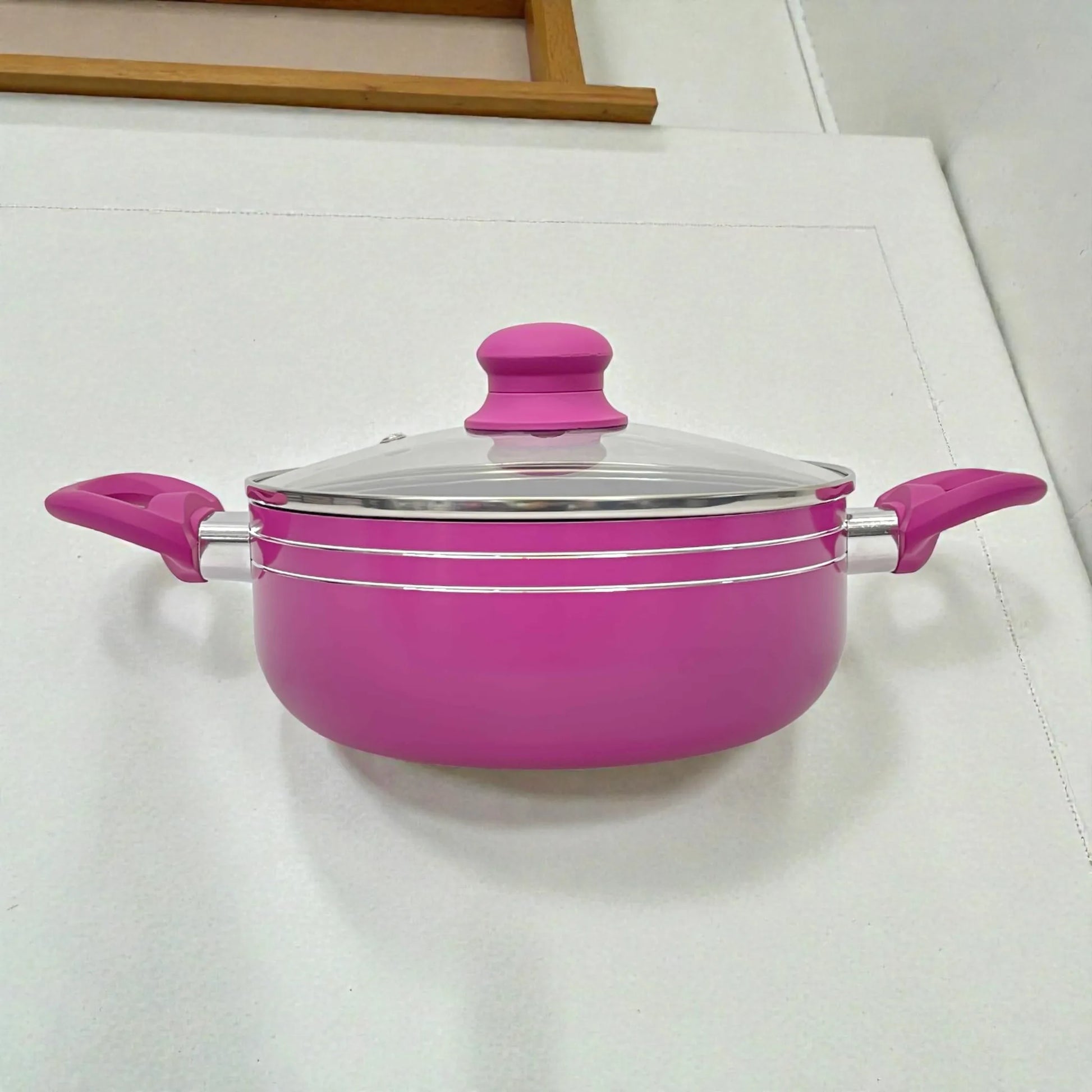 Cacerola u olla Bergmann de aluminio antiadherente color fucsia con tapa de vidrio templado y asas laterales resistentes al calor, vista frontal.