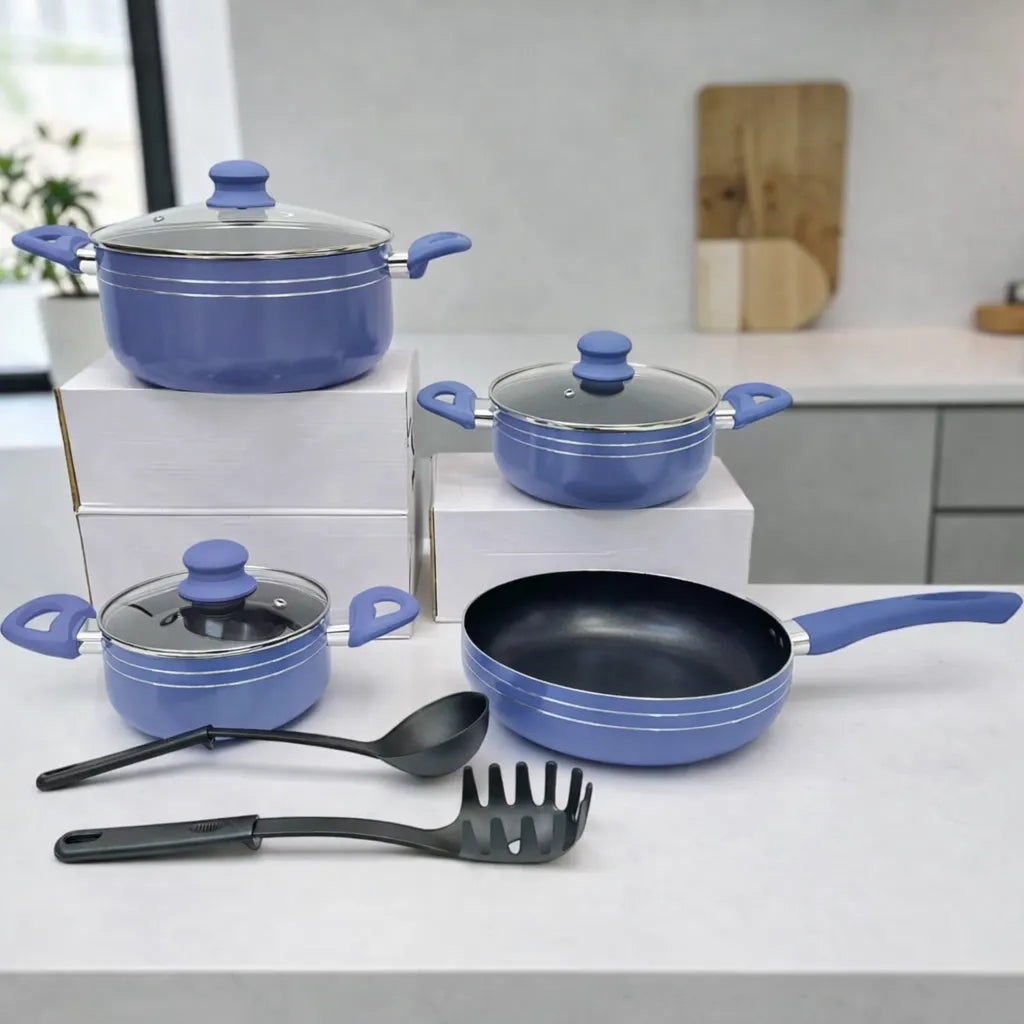 Set de ollas y sartén Bergmann color azul con tapas de vidrio y utensilios, exhibido sobre cajas en cocina.