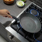 Sartén Bergner Orion Ø32 cm aluminio forjado con recubrimiento Marble+ gris, mostrada inclinada sobre estufa de gas para resaltar profundidad.