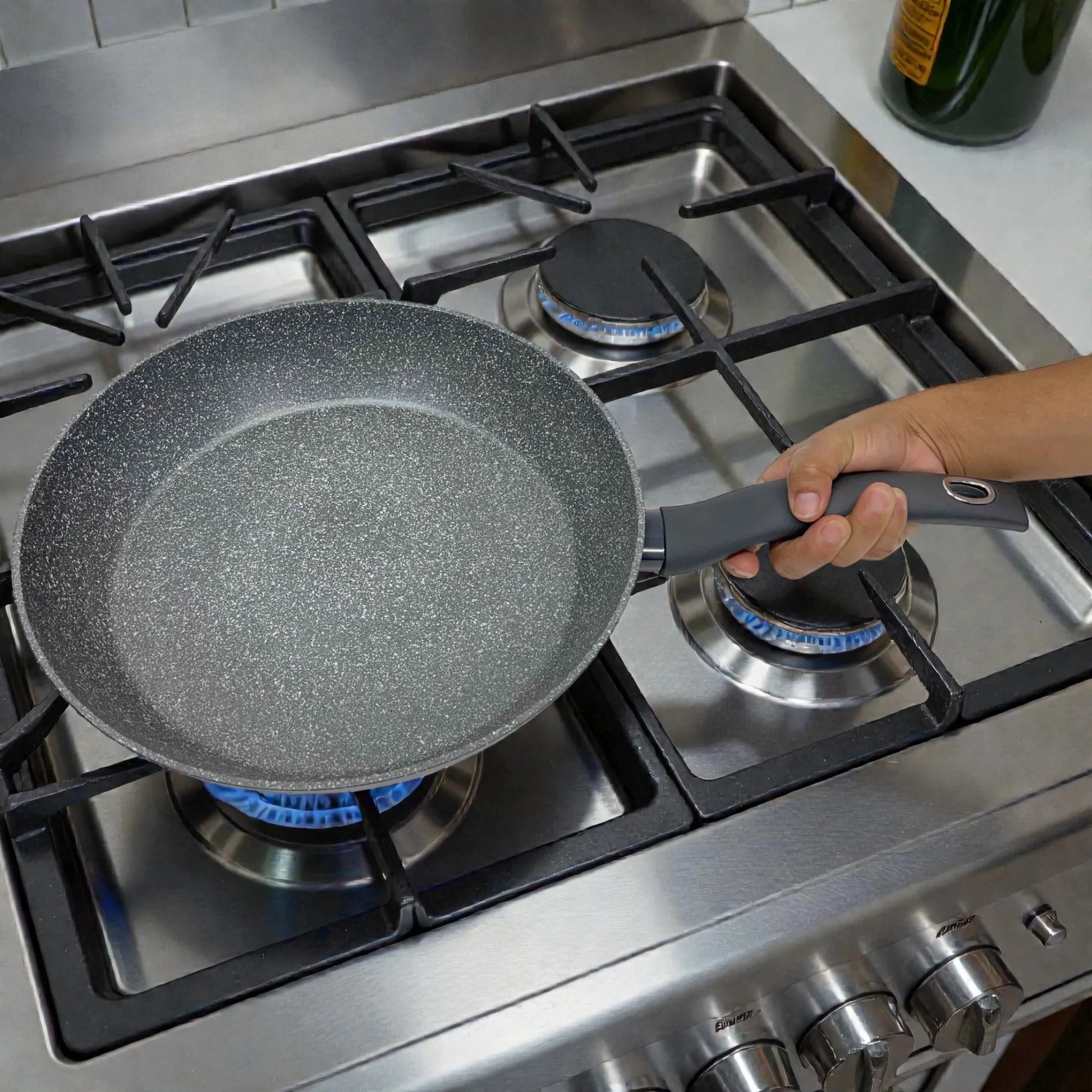 Sartén Bergner Orion Ø32 cm gris tipo piedra, sostenida por el mango en estufa de gas de acero inoxidable, interior antiadherente Marble+.