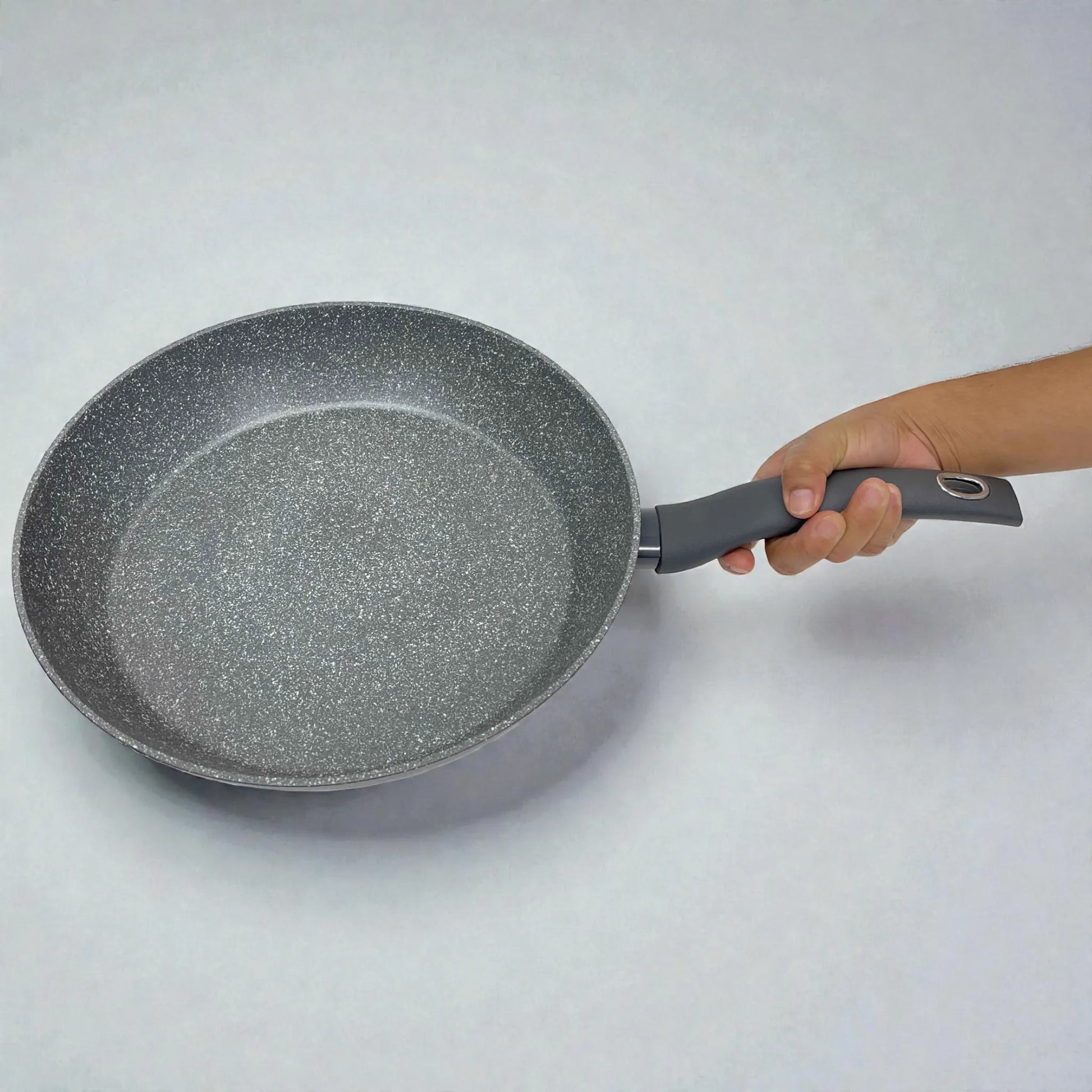 Sartén Bergner Orion Ø32 cm gris tipo piedra con antiadherente Marble+, vista superior en fondo blanco y sostenida por la mano para escala.